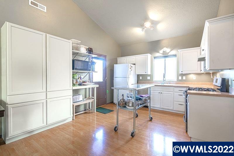 1569 Briar Road Independence, OR 97351 - Photo 7 of 24 a kitchen with a refrigerator a stove and white cabinets with wooden floor