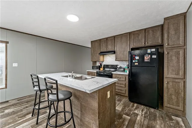 a kitchen with a refrigerator a stove a sink and a refrigerator with wooden floor