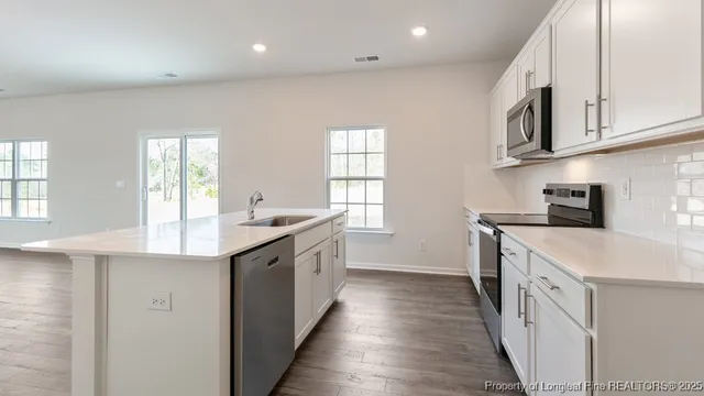 a kitchen with stainless steel appliances granite countertop a sink and dishwasher a stove a oven with wooden floors
