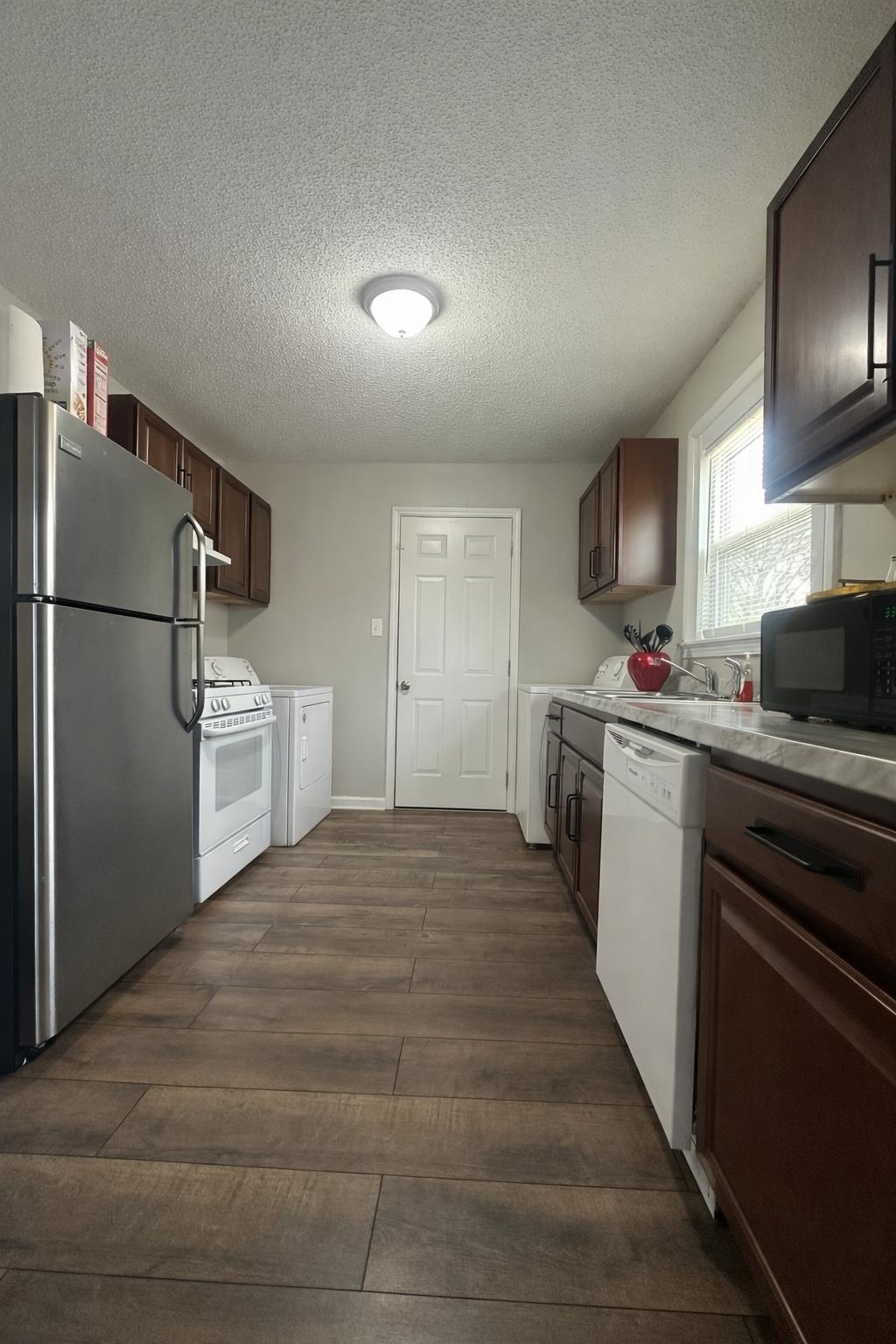 3534 Rochester Road Memphis, TN 38109 - Photo 5 of 13 Kitchen featuring white appliances, a textured ceiling, dark wood-type flooring, dark wood finish cabinets, and light countertops
