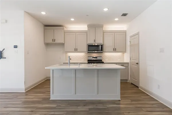 a kitchen with stainless steel appliances granite countertop a sink a stove a refrigerator and cabinets