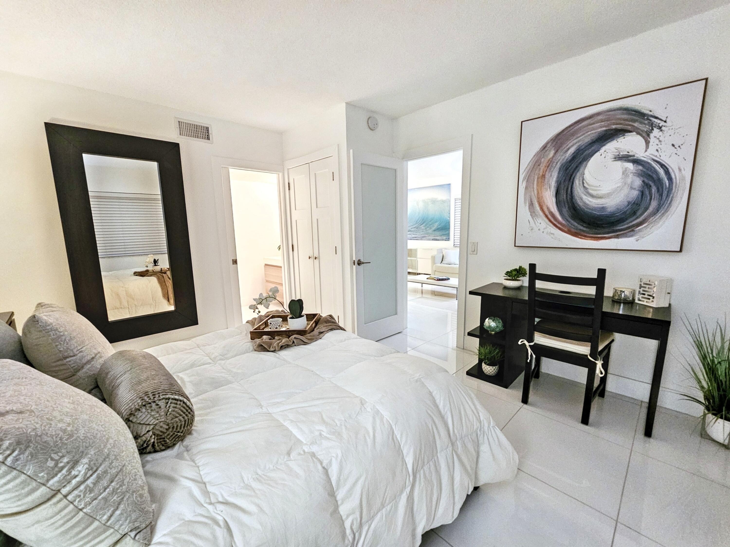 6530 North Ocean Boulevard, Unit 1080 Ocean Ridge, FL 33435 - Photo 24 of 54 a bedroom with a bed a mirror and a large mirror