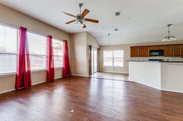 a view of an empty room with a window and wooden floor