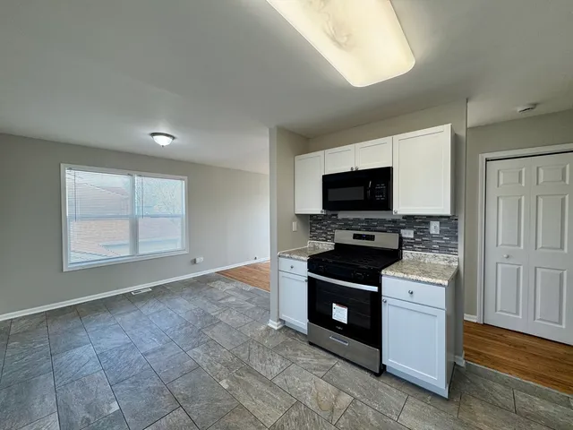 a kitchen with granite countertop a stove and a microwave