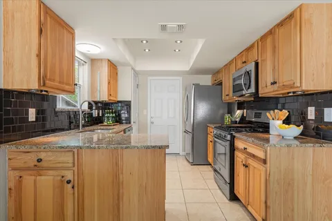 a kitchen with stainless steel appliances granite countertop a stove a sink and a refrigerator