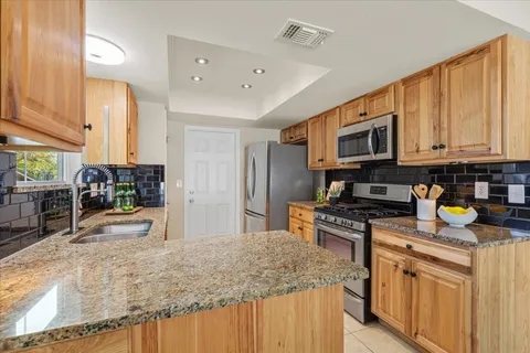 a kitchen with stainless steel appliances granite countertop a stove top oven a sink a counter space and cabinets