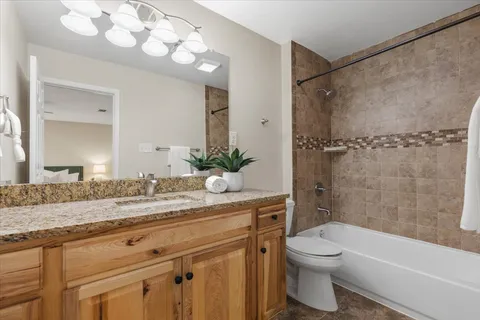 a bathroom with a granite countertop sink a toilet and shower