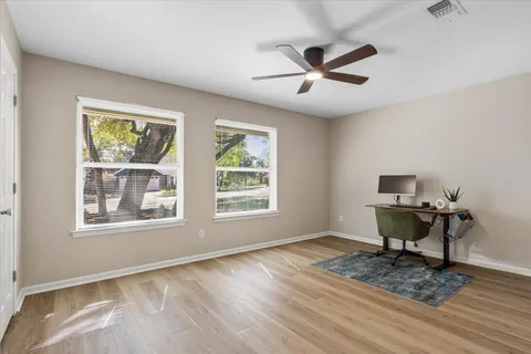 a workspace with wooden floor a ceiling fan and a window