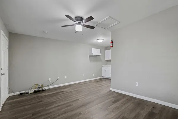 an empty room with wooden floor and fan