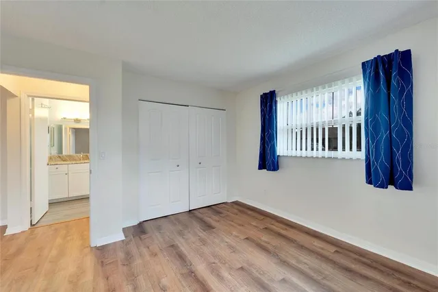 a view of an empty room with wooden floor and closet