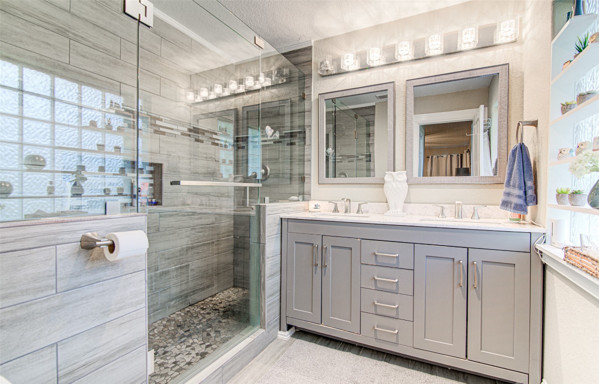 a bathroom with a double vanity sink mirror and shower