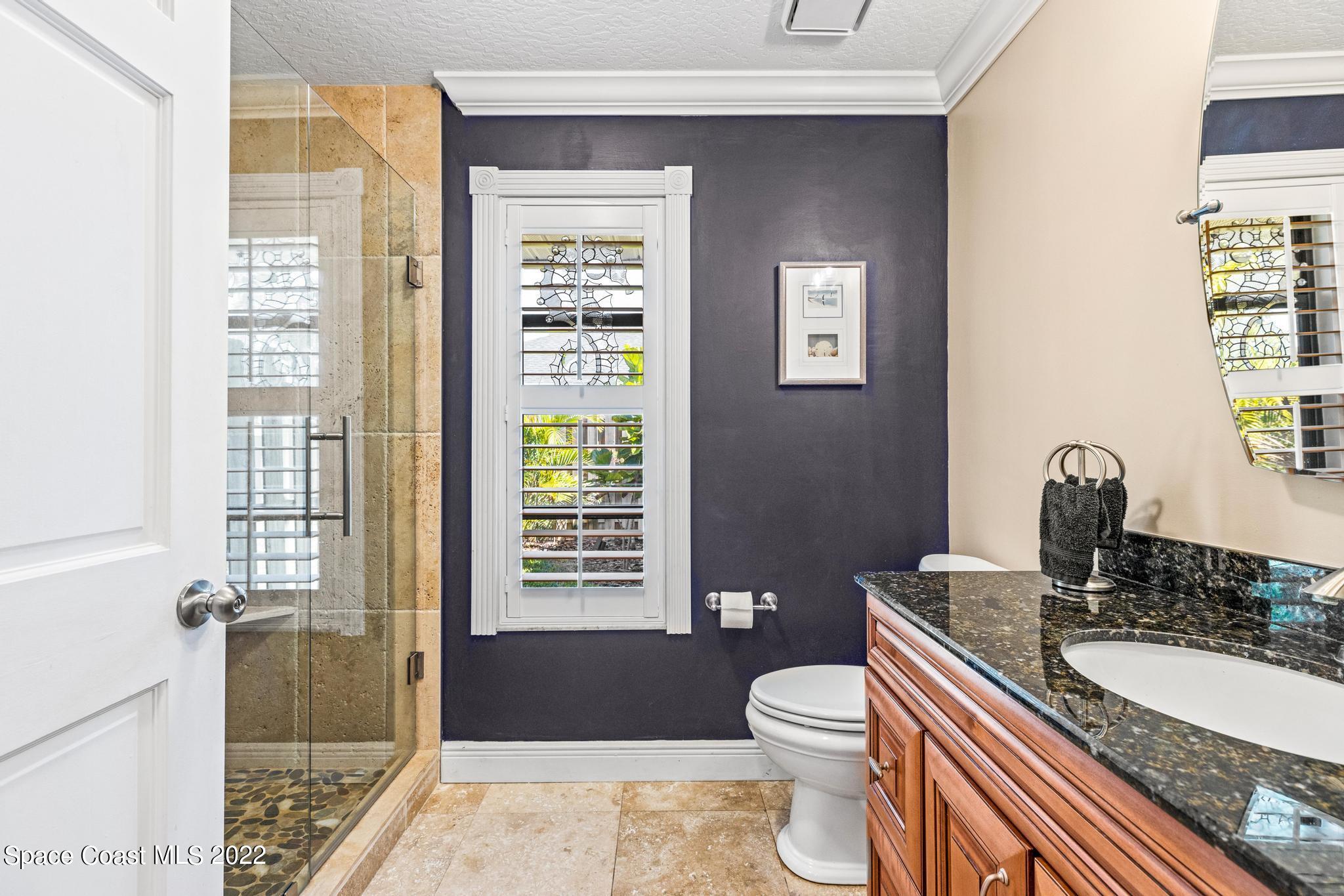 470 Veracruz Boulevard Indialantic, FL 32903 - Photo 12 of 25 a bathroom with a granite countertop toilet a sink a mirror a vanity and next to a window