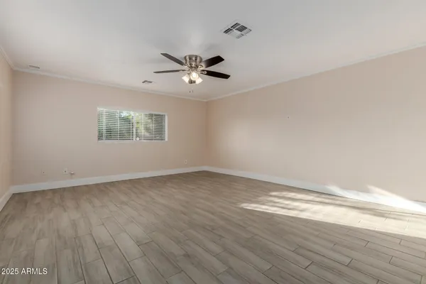 a view of an empty room with wooden floor and a window
