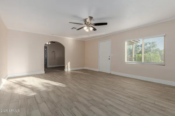 an empty room with wooden floor ceiling fan and windows