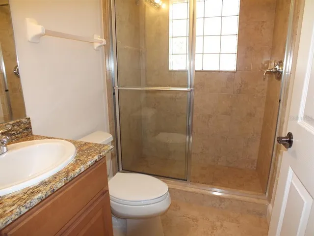 a bathroom with a granite countertop toilet a sink and shower