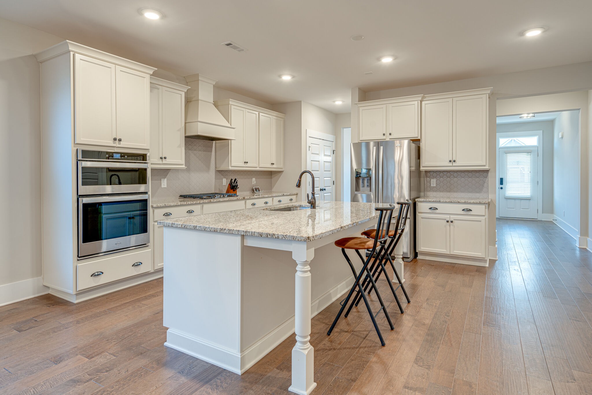 a kitchen with stainless steel appliances granite countertop a white cabinets and wooden floors