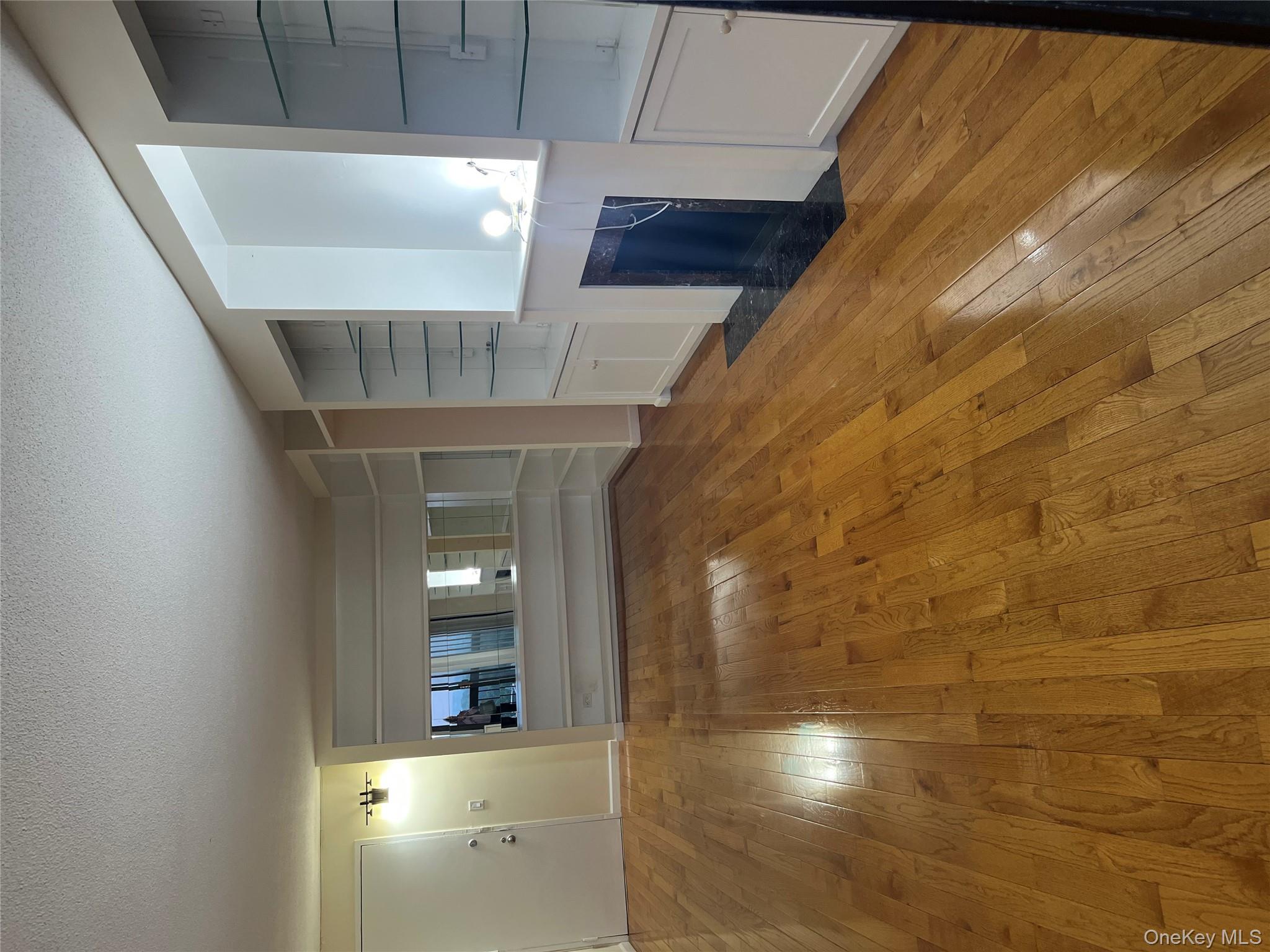 2 Bay Club Drive, Unit 16N Queens, NY 11360 - Photo 2 of 16 Unfurnished living room featuring wood-type flooring, a textured ceiling, a fireplace with flush hearth, and built in features