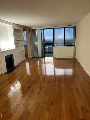a view of an empty room with window and wooden floor