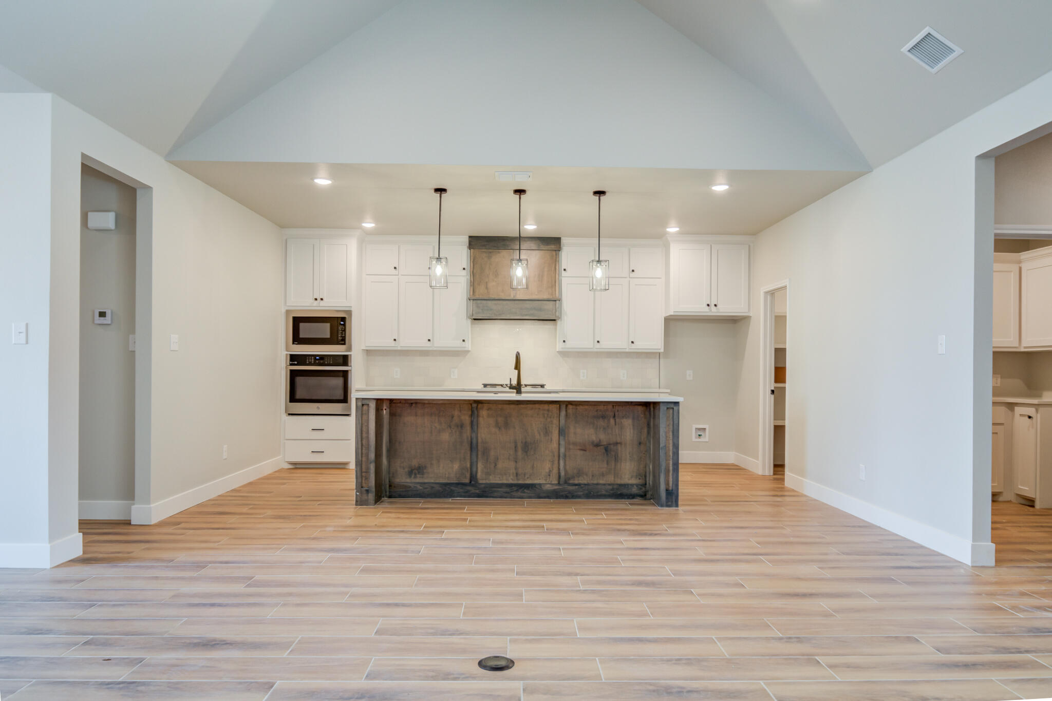 7805 54th Street Lubbock, TX 79407 - Photo 16 of 55 a large kitchen with stainless steel appliances kitchen island a sink dishwasher a refrigerator and a oven with wooden floor