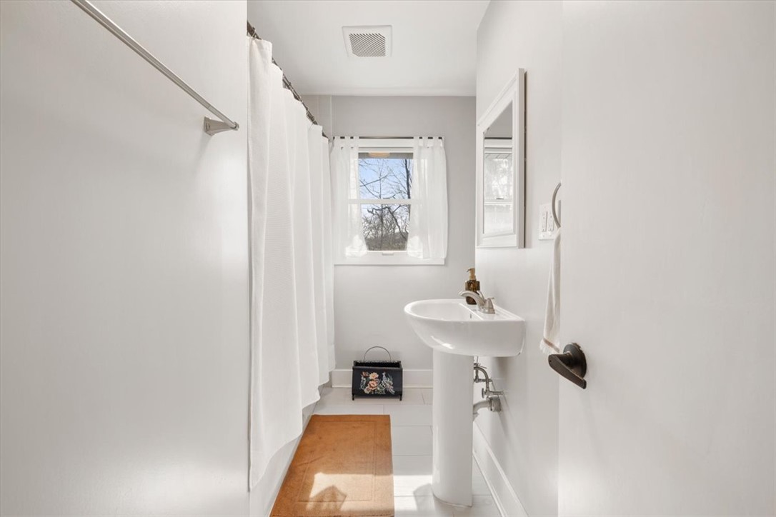 9555 Clyo Road Dayton, OH 45458 - Photo 17 of 31 This bright bathroom features a pedestal sink and window, creating a refreshing atmosphere.
