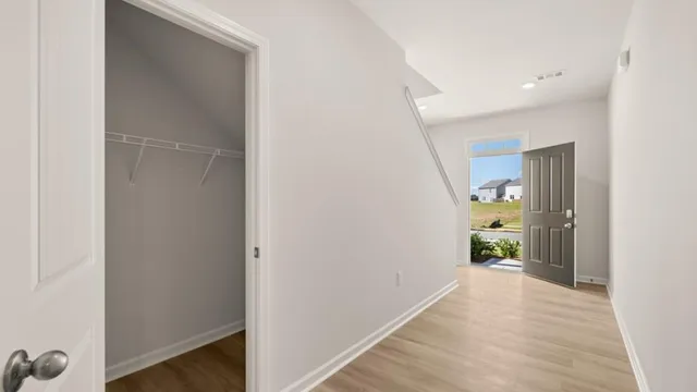a view of a hallway with wooden floor and a bathroom