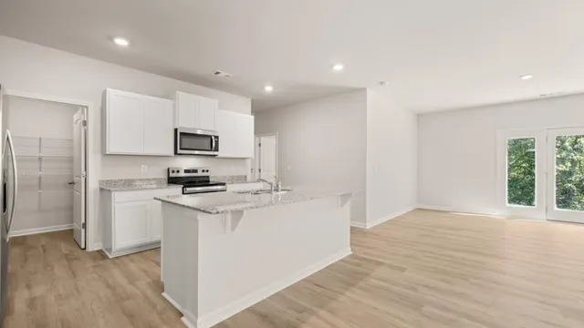 a kitchen with stainless steel appliances a stove top oven a sink a refrigerator a center island and cabinets