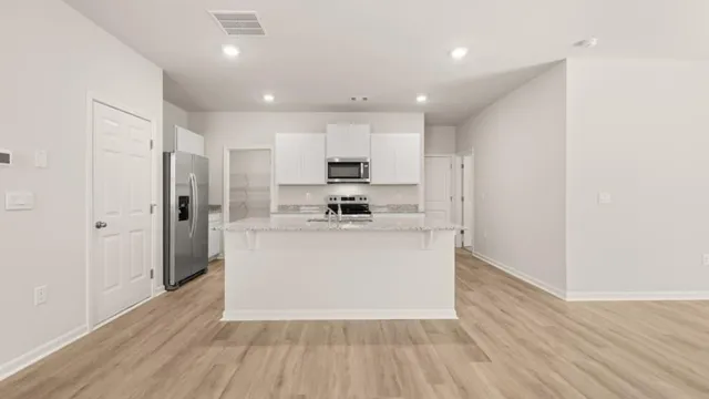 a view of kitchen with stainless steel appliances granite countertop refrigerator stove top oven and cabinets