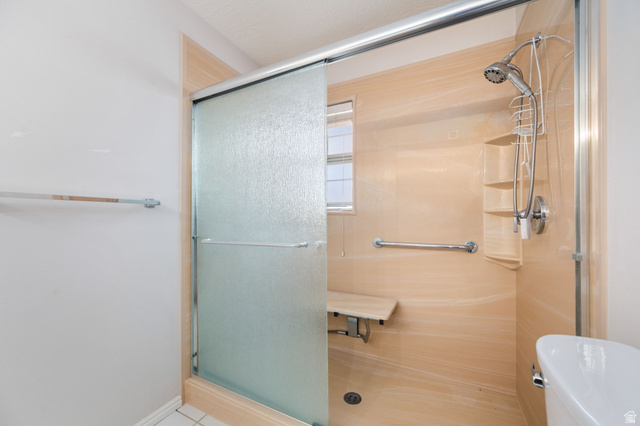 39 North Valley View Drive, Unit 51 St. George, UT 84770 - Photo 20 of 25 Walk-in shower featuring a sliding frosted glass door, light-toned shower surround, built-in shelving, chrome fixtures, and a folding shower bench