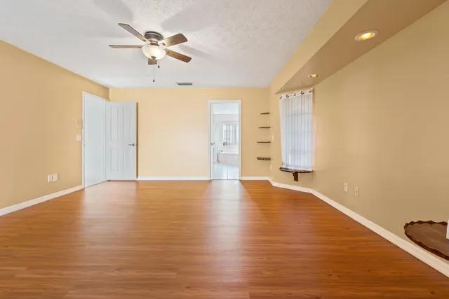 a view of an empty room with window and wooden floor