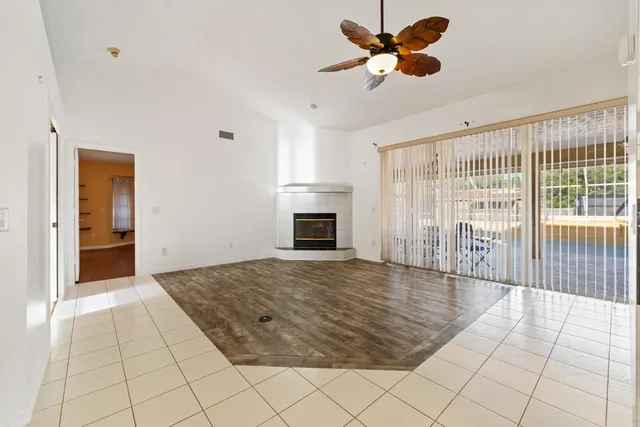 a view of an empty room with a fireplace and a chandelier fan