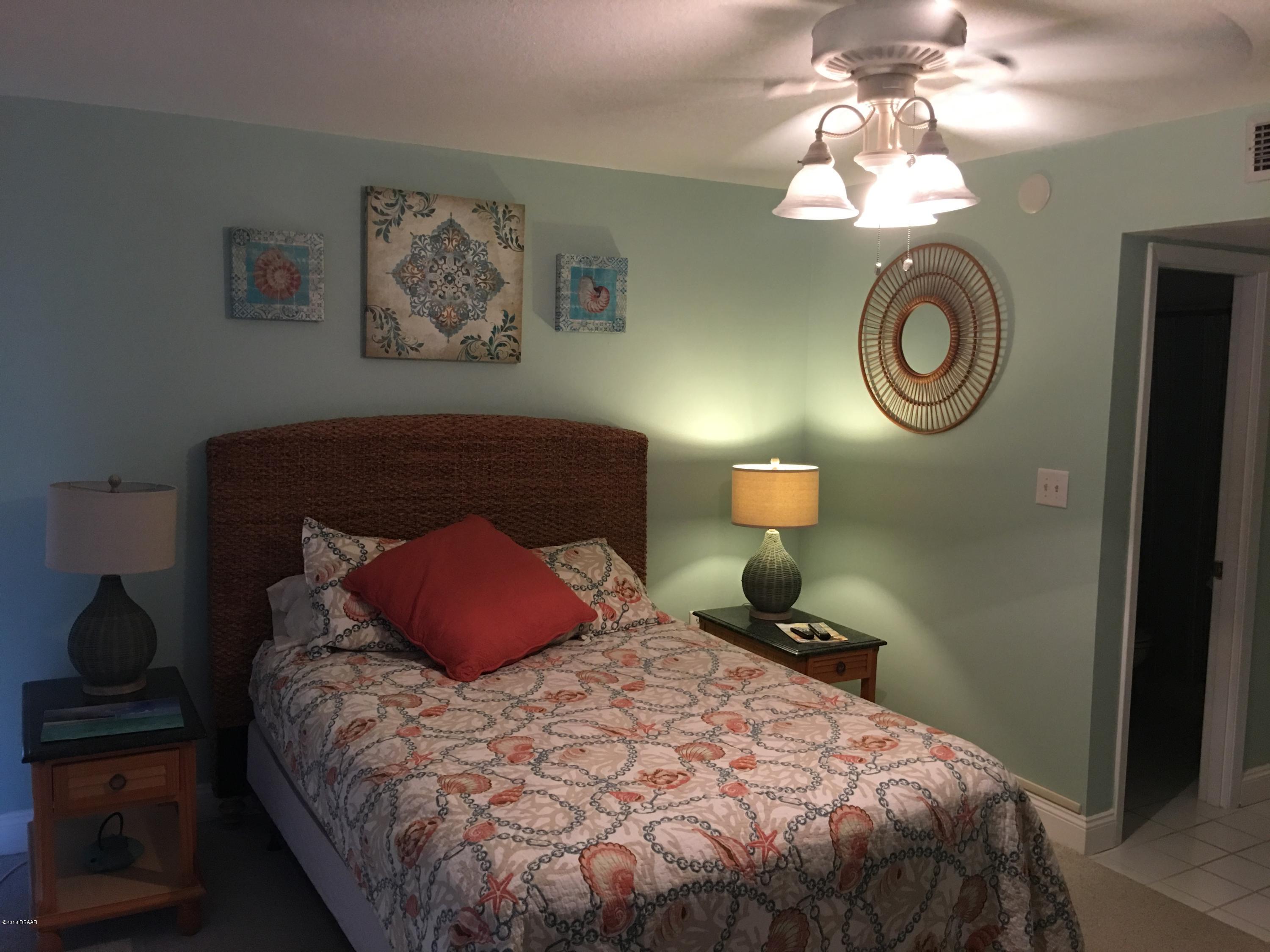 5500 Ocean Shore Boulevard, Unit 52 Ormond Beach, FL 32176 - Photo 19 of 33 a bedroom with a bed and a chandelier