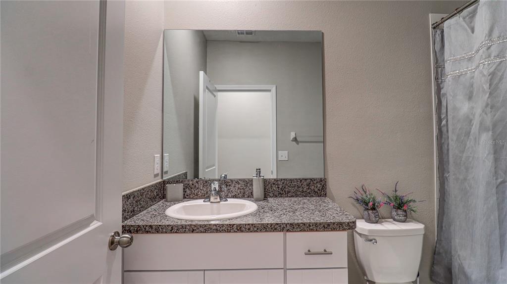 31632 Blue Passing Loop Wesley Chapel, FL 33545 - Photo 44 of 48 a bathroom with a granite countertop sink and a mirror