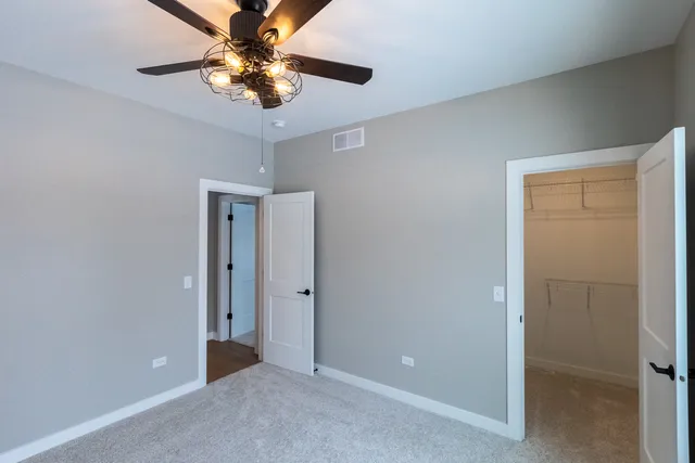 a view of an empty room and chandelier fan