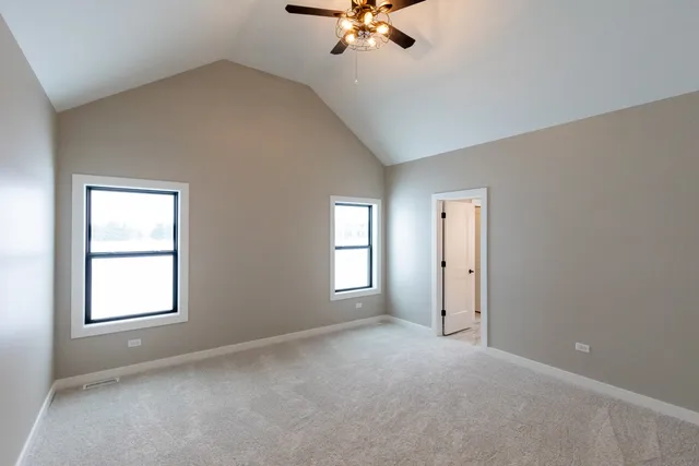 an empty room with chandelier fan and windows