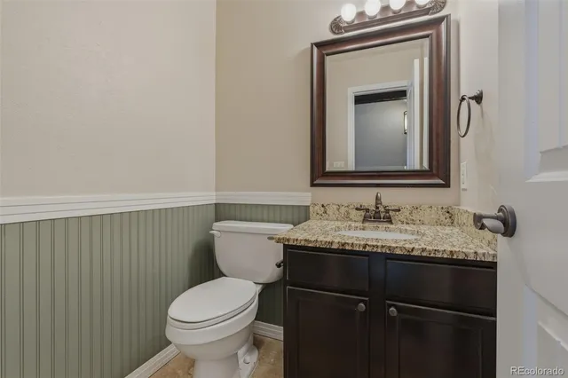 a bathroom with a granite countertop toilet sink and mirror