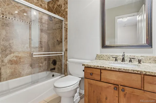 a bathroom with a granite countertop sink toilet mirror vanity and bathtub