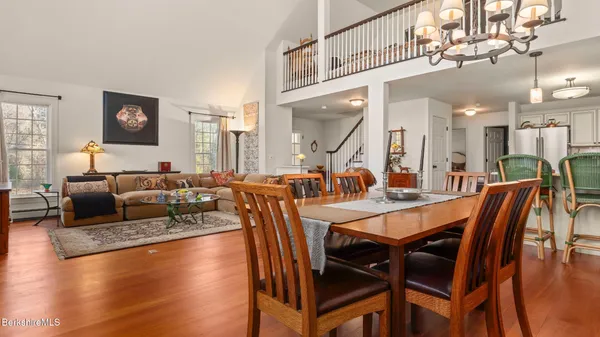 a view of a dining room and livingroom with furniture wooden floor a rug a fireplace and a chandelier
