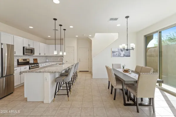 a kitchen with stainless steel appliances kitchen island granite countertop a table chairs and a refrigerator
