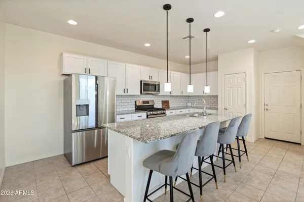 a kitchen with stainless steel appliances granite countertop a refrigerator a stove a sink a microwave and a refrigerator