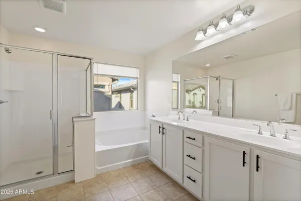 a spacious bathroom with a double vanity sink a mirror and a bathtub