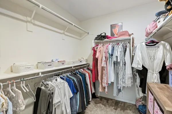 a view of walk in closet with clothes and shoes
