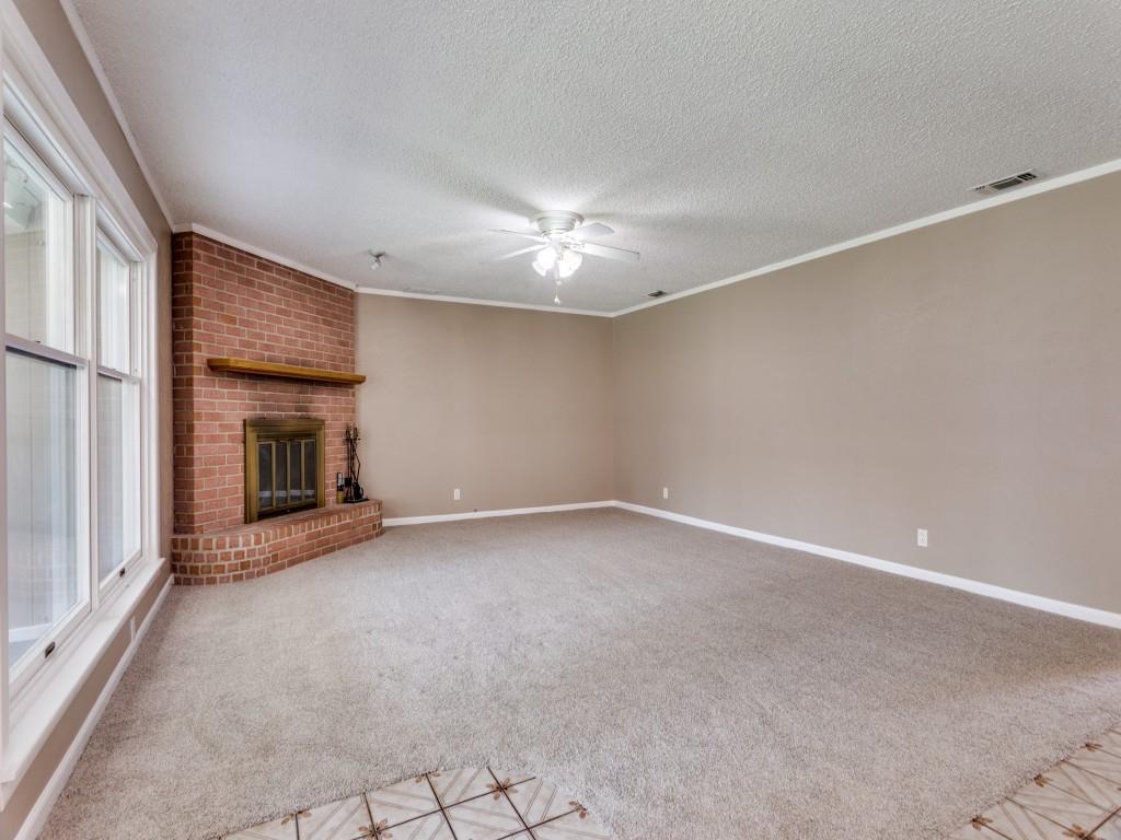 1216 Manning Street Benbrook, TX 76126 - Photo 6 of 26 Unfurnished living room featuring crown molding, light colored carpet, a fireplace, a textured ceiling, and a ceiling fan