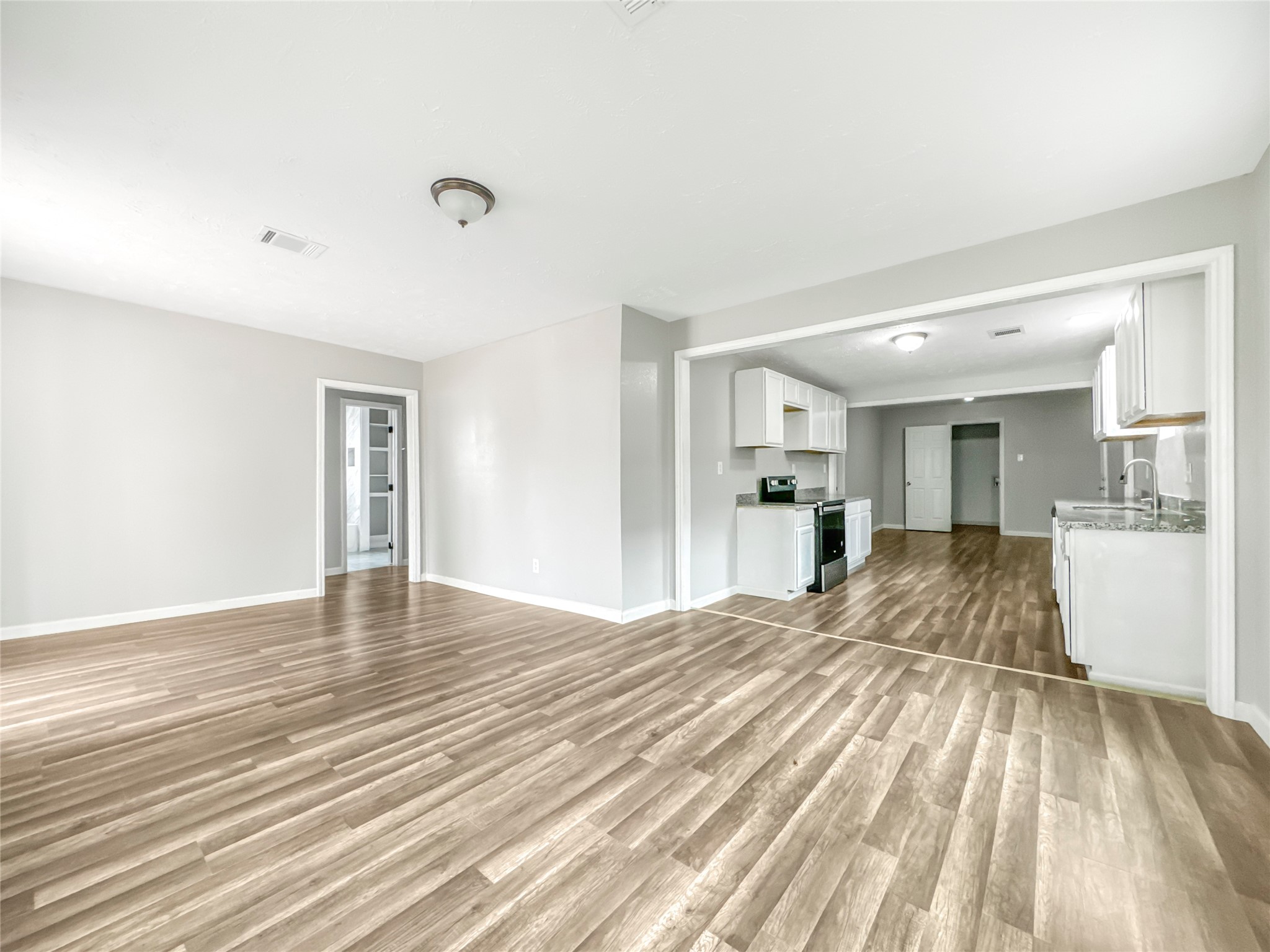 306 Armstrong Street Houston, TX 77029 - Photo 3 of 30 a view of empty room with wooden floor and kitchen view
