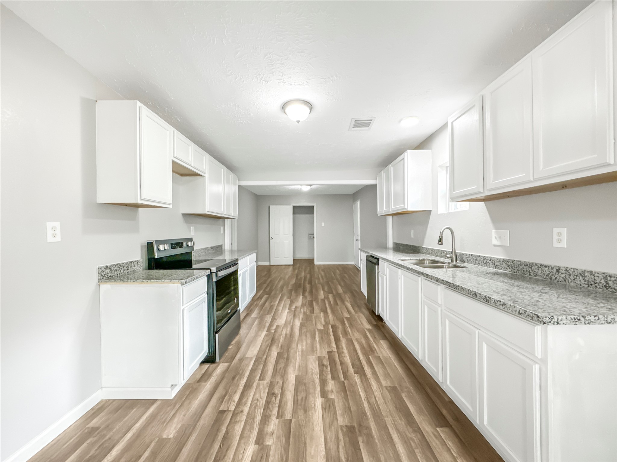 306 Armstrong Street Houston, TX 77029 - Photo 5 of 30 a white kitchen with wooden floor and stainless steel appliances