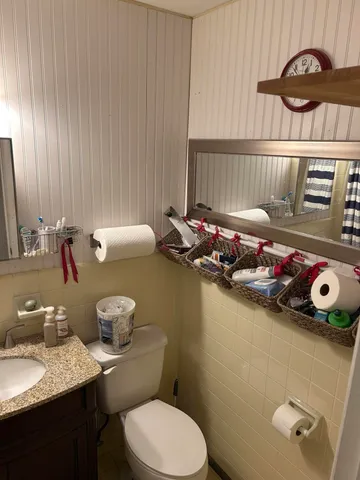 a bathroom with a granite countertop sink and a toilet