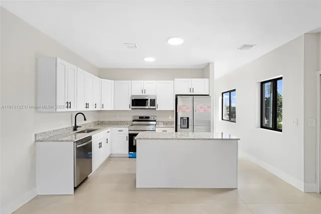 a kitchen with stainless steel appliances granite countertop a sink stove refrigerator and cabinets