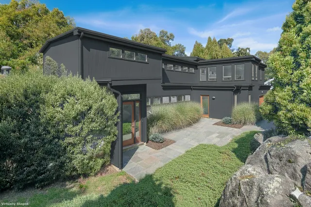 a view of a house with a small yard plants and large tree