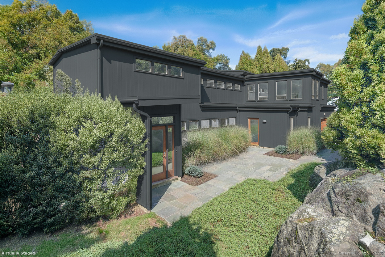 a view of a house with a small yard plants and large tree