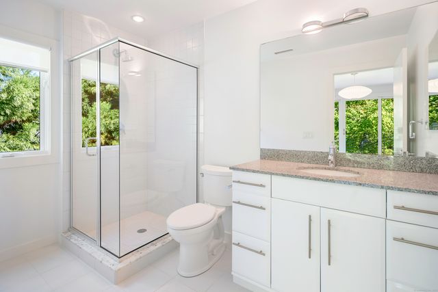 a bathroom with a granite countertop sink a toilet and shower