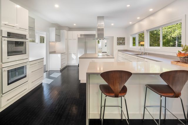 a kitchen with stainless steel appliances kitchen island a table and chairs in it